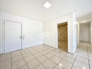Vista de um corredor interno com piso de cerâmica e portas brancas.