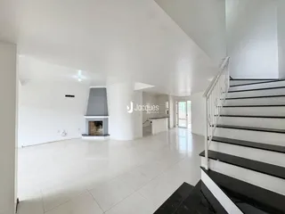 Vista ampla de uma sala de estar com piso de cerâmica e escadaria.