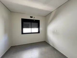 Uma sala de estar com paredes brancas e piso cinza.