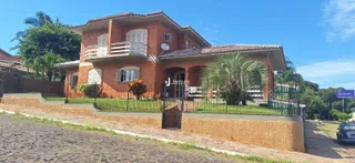Fachada de casa em tijolo vermelho com cerca e jardim.