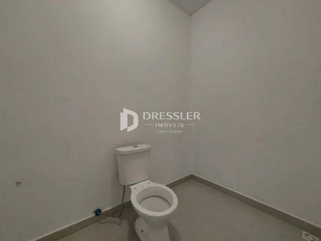Foto interna de um banheiro com vaso sanitário e piso claro.