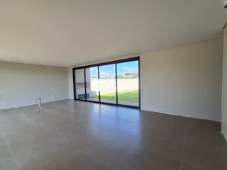 Sala de estar ampla com piso de concreto e porta de vidro voltada para um jardim.