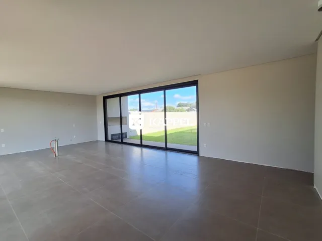 Sala de estar ampla com piso de concreto e porta de vidro voltada para um jardim.