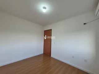 Interior de um cômodo com piso de madeira e parede branca.