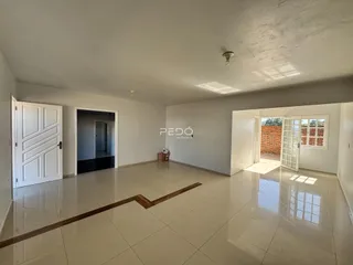 Interior de uma sala ampla com piso de cerâmica e paredes brancas.
