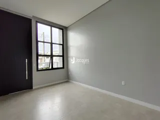 Foto de um cômodo interno com paredes cinzas e uma grande janela.