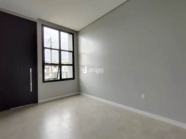 Foto de um cômodo interno com paredes cinzas e uma grande janela.