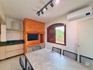 Foto de uma sala de jantar com parede de tijolos aparentes e janela no interior de uma residência.