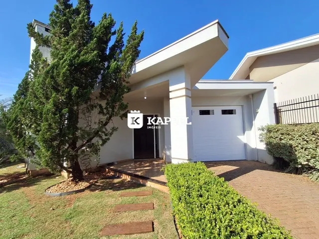Fachada frontal de uma residência branca com jardim e garagem.