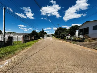 Vista de uma rua pavimentada em Lajeado, Brasil, com postes de luz e vegetação ao redor.