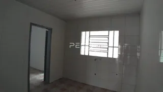 Vista interna de um corredor com paredes brancas e piso de cerâmica.