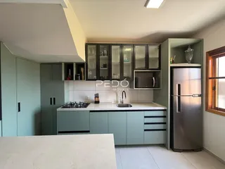 Cozinha moderna com armários verdes e bancada branca.