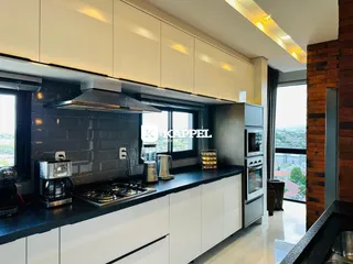 Cozinha moderna com armários brancos e bancadas escuras em um apartamento em Lajeado.