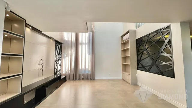 Ambiente interno de uma sala com piso claro e paredes brancas.