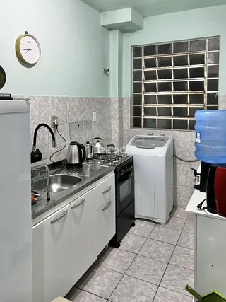 Foto de uma cozinha com bancada de aço inoxidável e armários brancos.