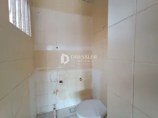 Foto de um banheiro com paredes de azulejo brancas e um vaso sanitário.