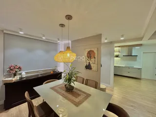 Sala de jantar com mesa de madeira e luminária pendente em um imóvel no Brasil.