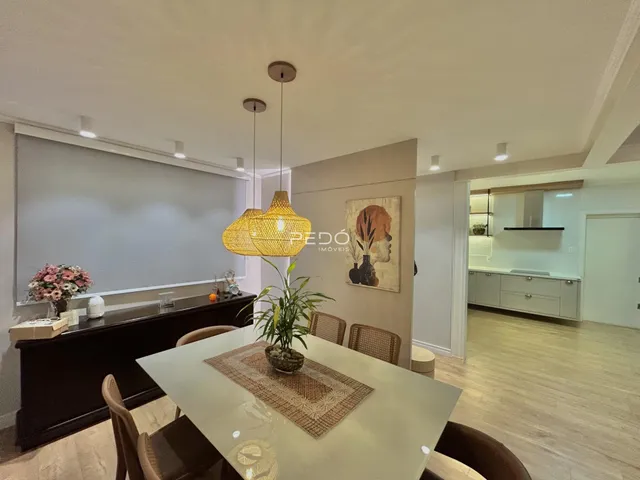 Sala de jantar com mesa de madeira e luminária pendente em um imóvel no Brasil.