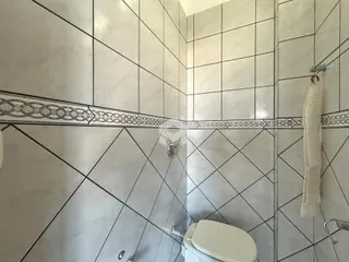 Parede de um banheiro com revestimento de azulejos brancos.