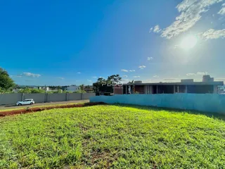 Paisagem de grama verde com uma cerca azul e um edifício ao fundo.