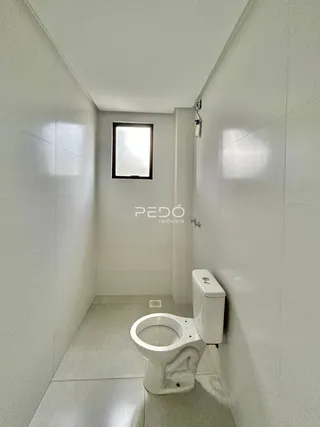 Foto de um corredor com um vaso sanitário branco em um imóvel.