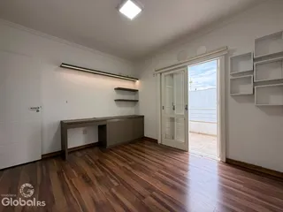 Sala de estar com piso de madeira e área de passagem para a varanda.