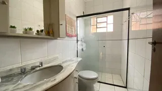 Banheiro com box de vidro e bancada de mármore.
