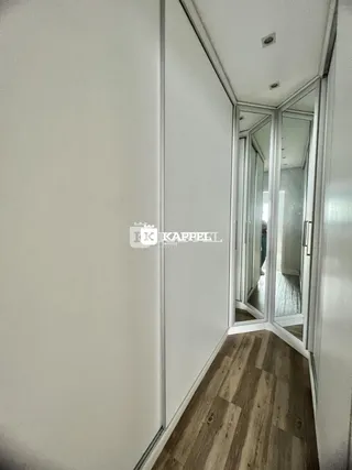 Hall de entrada com piso de madeira e espelho refletindo o ambiente.