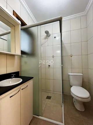 Foto de um banheiro com revestimento cerâmico e box de vidro.
