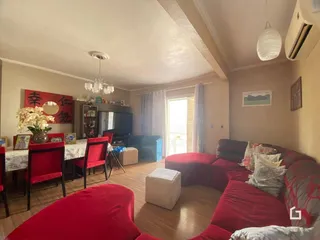 Sala de estar com móveis vermelhos e piso de madeira.