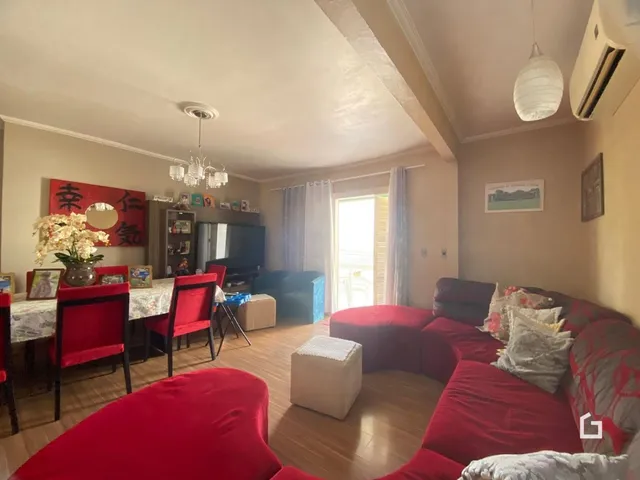 Sala de estar com móveis vermelhos e piso de madeira.