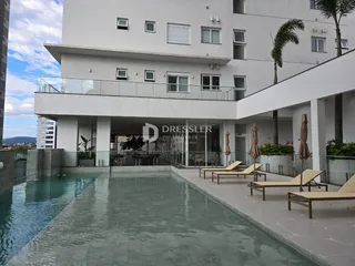 Foto da fachada de um prédio com piscina e área externa.