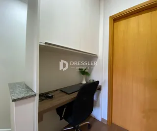 Interior de um ambiente com armários brancos e uma mesa de trabalho de madeira.
