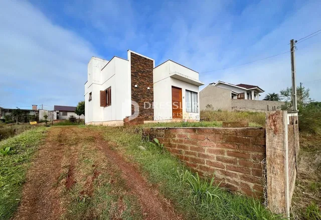 Fachada de uma residência em Lajeado, Brasil, com muro de tijolos e vegetação ao redor.
