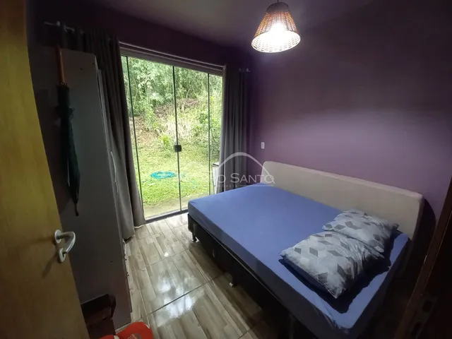 Quarto com cama e porta de vidro que dá acesso ao jardim.