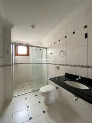A foto mostra o interior de um banheiro com revestimento cerâmico e box de vidro.