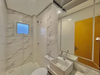 Banheiro com revestimento de azulejos brancos e piso claro.