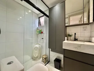 Banheiro moderno com box de vidro e revestimento branco.