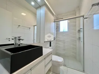 Banheiro moderno com revestimento cerâmico e box de vidro.