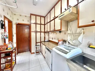 Vista da cozinha com armários de madeira e revestimento cerâmico.