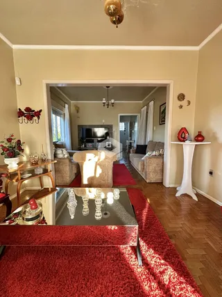 Interior de uma sala de estar com porta de entrada aberta.