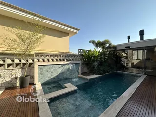 Vista externa de uma piscina com deck de madeira e jardim em Lajeado.