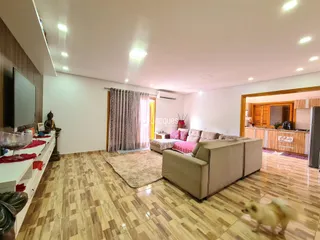 Sala de estar ampla com piso de madeira e sofá claro.