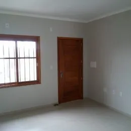Interior de um cômodo com paredes claras e uma porta de madeira escura.