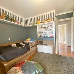 Quarto com cama de madeira e painel decorativo na sala.