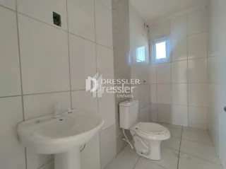 Banheiro com revestimento cerâmico branco nas paredes.