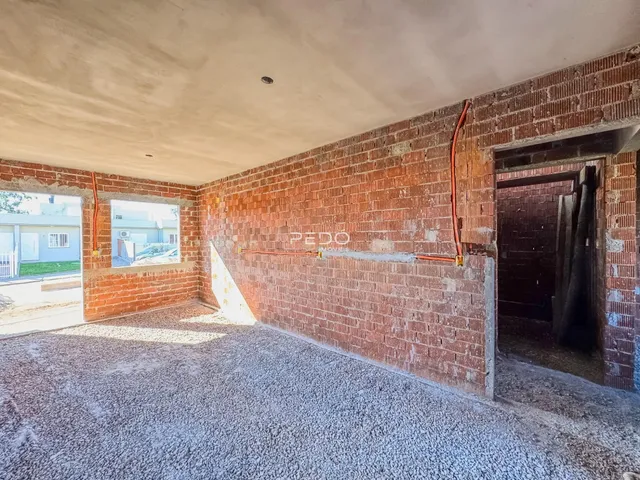 Interior de uma sala com paredes de tijolo aparente e piso de cascalho.