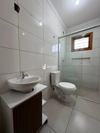 Foto de um banheiro com revestimento branco e box de vidro.