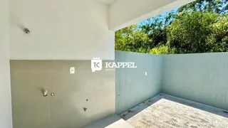 Foto de um corredor interno com parede branca e acesso a uma área externa verde.
