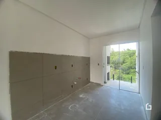 Vista interna de um ambiente com paredes brancas e piso de concreto.